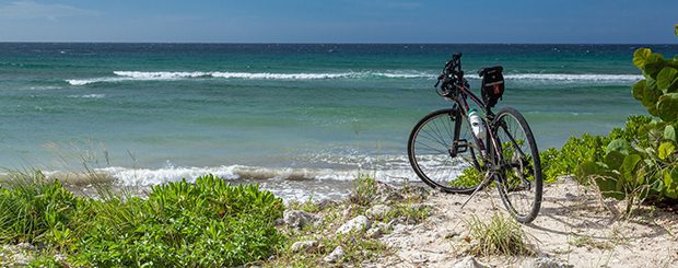 A bicycle parked on the beach near the ocean.