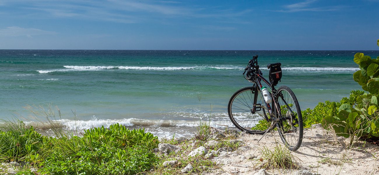 A bicycle parked on the beach near the ocean.